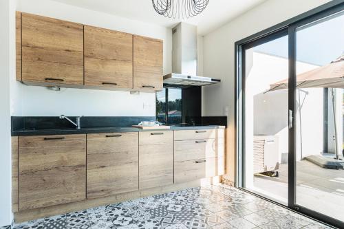 a kitchen with wooden cabinets and a large window at Belle Villa, Evasion Landaise in Azur