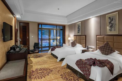 um quarto de hotel com três camas e uma televisão em Avatar Valley Grand Hotel em Zhangjiajie