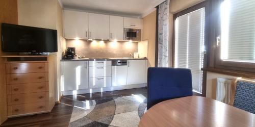 eine Küche mit weißen Schränken, einem Tisch und einem blauen Stuhl in der Unterkunft Appartements Kuprian in Längenfeld