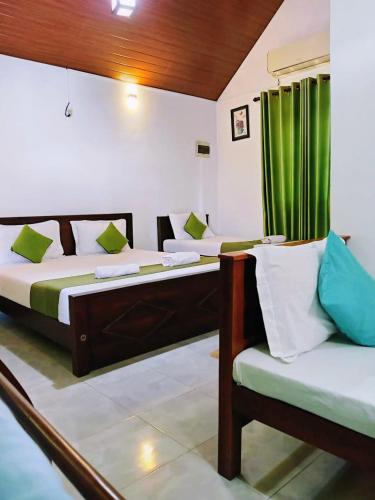 two beds in a room with green curtains at Ranweli Resort Anuradhapura in Anuradhapura