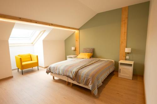 a bedroom with a bed and a yellow chair at Le 240, entre lac et montagnes in Les Rousses