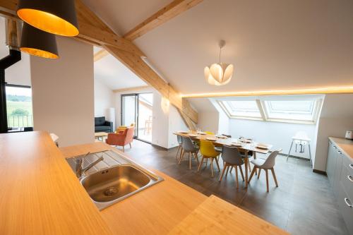 a kitchen and dining room with a sink in the middle at Le 240, entre lac et montagnes in Les Rousses