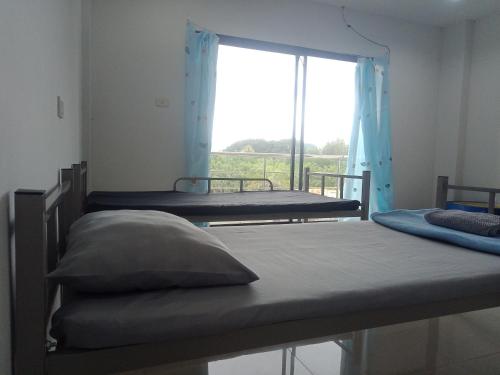 deux lits dans une chambre avec une fenêtre dans l'établissement มังกรเลโฮลเทลกระบี่ Mangkonlay Hostel Krabi, à Ban Khlong Chi Lat