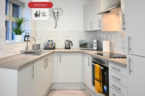 a kitchen with white cabinets and a counter top at Jungle King Suite with Parking in Bedford