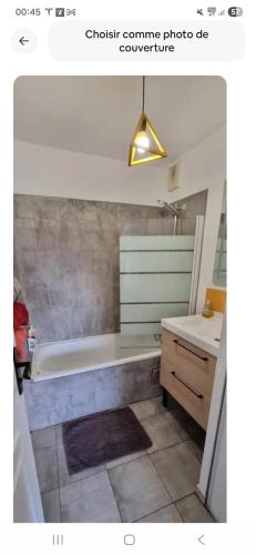 a bathroom with a bath tub and a sink at Appartement Lovely in Muret