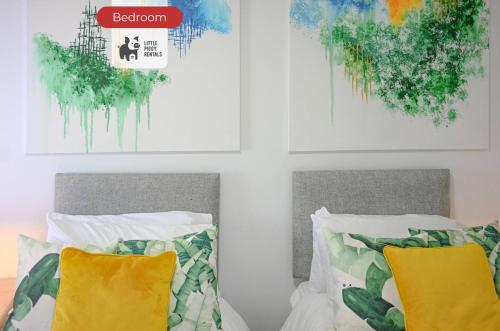 a bedroom with two beds and two paintings on the wall at Central Balcony Flat Ideal for Long Stays with WiFi and Parking in Bedford