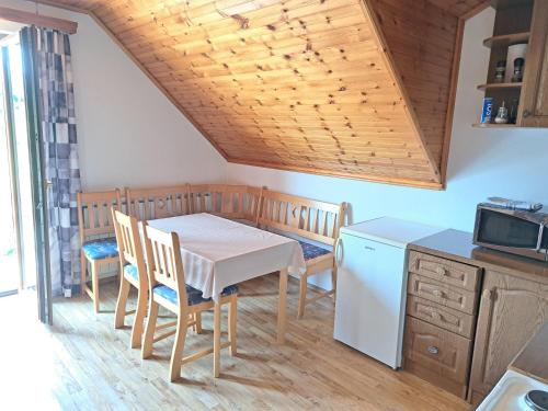 een keuken met een tafel, stoelen en een magnetron bij Guesthouse Zafran in Smoljanac