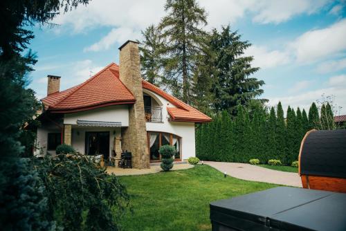 a house with a red roof and a yard at Zarabie Residence in Myślenice