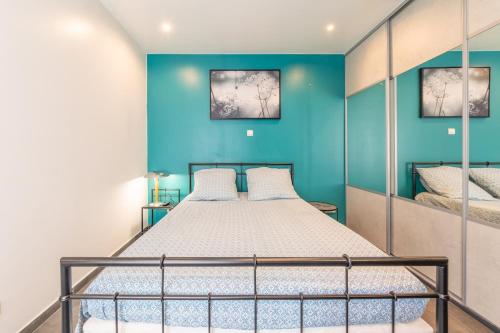 a bedroom with a bed and a blue wall at Maison calme, lumineuse & design in Sevran