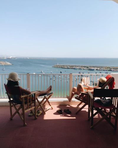 three people sitting in chairs on a balcony looking at the ocean at Manas Slowliving - Sines in Sines