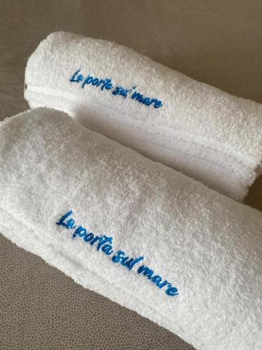 two white towels with blue writing on them at B&B La Porta sul Mare a Porto Cesareo in Torre Squillace