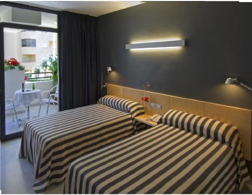 two beds in a hotel room with striped sheets at Hotel Nautico in Santa Cruz de Tenerife