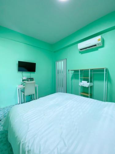 een slaapkamer met een wit bed en een televisie bij Luigi Guest House & Kitchen in Sattahip