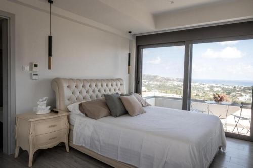 a bedroom with a white bed and a large window at Aetheria Luxury Villa in Kalithies