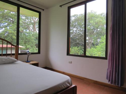 a bedroom with a bed and two windows with trees at Quinta Celeste in La Garita