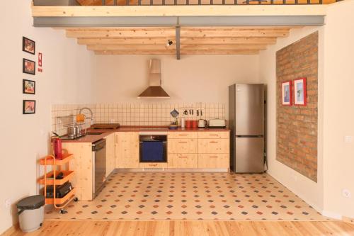 a kitchen with wooden cabinets and a refrigerator at Manas Slowliving - Santiago in Santiago do Cacém