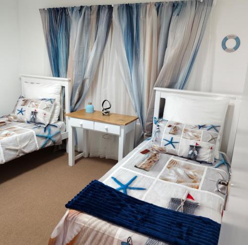 een slaapkamer met 2 aparte bedden en een tafel bij Dunes Alcove Mossel Bay Comfortable self catering accommodation just 900 meters from the beach and close to restaurants shops and local attractions in Vosburg