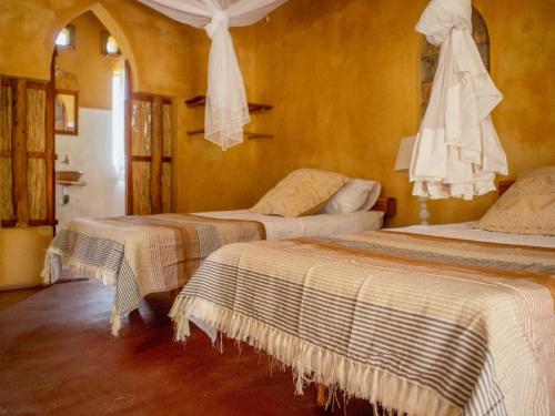 two beds in a room with yellow walls at Turtle Cove Self-Catering Lodge & Yoga Shala in Praia do Tofo