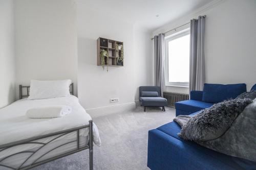 a bedroom with a bed and a blue couch at Seafront folkestone Sandgate channel tunnel - 5 star property Sleeps 16 in Sandgate