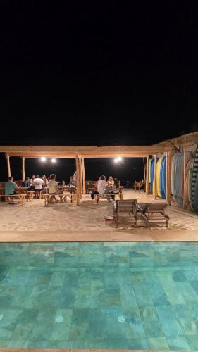 a group of people sitting at picnic tables near a pool at Aloha Imsouane vue sur mer in Imsouane