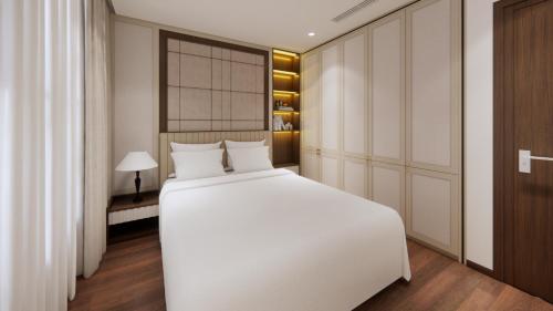 ein Schlafzimmer mit einem großen weißen Bett und einer Lampe in der Unterkunft Aravelle Suites in Hanoi