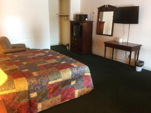 Habitación de hotel con cama, tocador y espejo en Budget inn en Lumberton