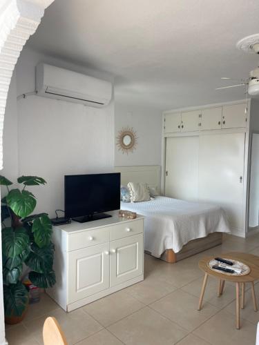 Schlafzimmer mit einem Bett und einem Schrank mit einem TV in der Unterkunft Estudio Miralmar in Torrox