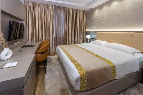 a hotel room with a large bed and a desk at Shkoder Grand Hotel Europa, Affiliated by Melia in Shkodër