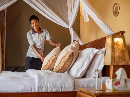 a man putting pillows on beds in a hotel room at Lake Chahafi Resort in Kisoro