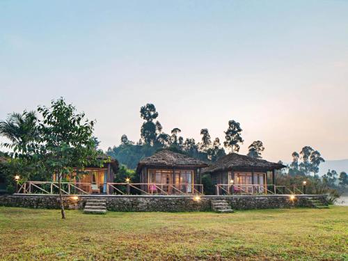 a resort with two huts in a field at Lake Chahafi Resort in Kisoro