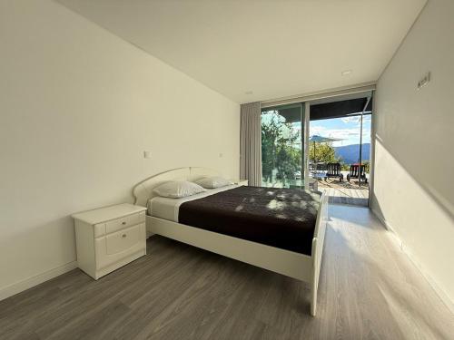 a bedroom with a bed and a large window at Villa Teixugueiras 1 - Gerês in Vieira do Minho