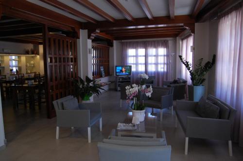 a living room with chairs and a table with flowers at Hotel Nettuno in Cala Gonone