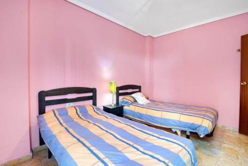 two beds in a room with pink walls at Paseo el Saladar in Denia