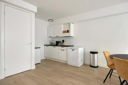 a kitchen with white cabinets and a table and chairs at Comfortable 1-Bedroom Flat in Central Rotterdam in Rotterdam