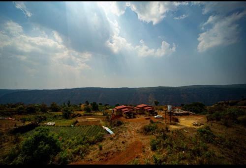 a view of a farm with mountains in the background at Savitri villa inn in Mahabaleshwar