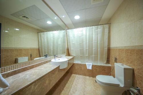 a bathroom with a sink and a toilet and a mirror at Ivory Grand Hotel Apartments in Dubai
