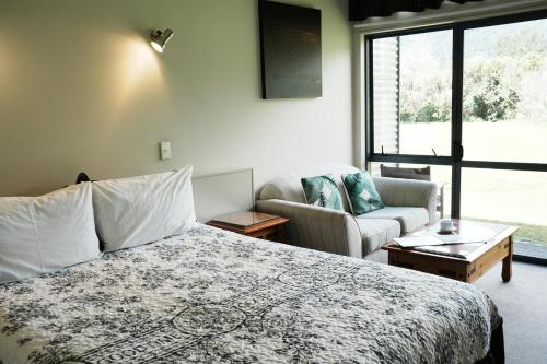 Un dormitorio con una cama y un sofá y una ventana. en Sunset Motel, en Fox Glacier