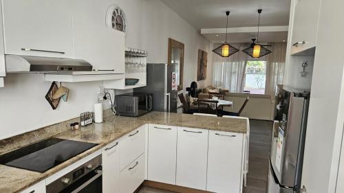 eine Küche mit weißen Schränken und ein Wohnzimmer in der Unterkunft Family Retreat - Pool - Gym - BBQ - Walk to Beach in Cap Malheureux