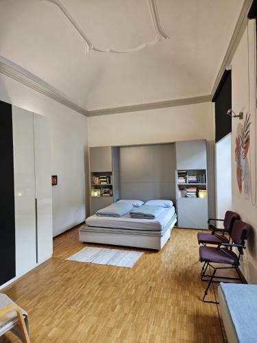 a bedroom with a bed and chairs in it at Bellinzona Piazza Collegiata in Bellinzona