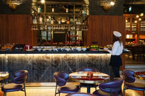 uma mulher parada em um bar em um restaurante em Radisson RED Tbilisi em Tbilisi