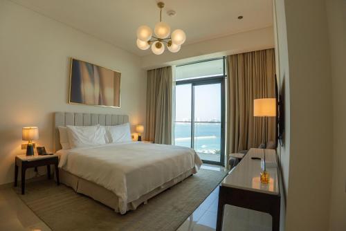 a hotel room with a bed and a large window at Address Beach Resort Residence Bahrain in Rayyā
