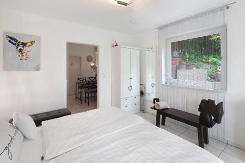 a white bedroom with a bed and a window at Ferienwohnung an der Dönche in Kassel