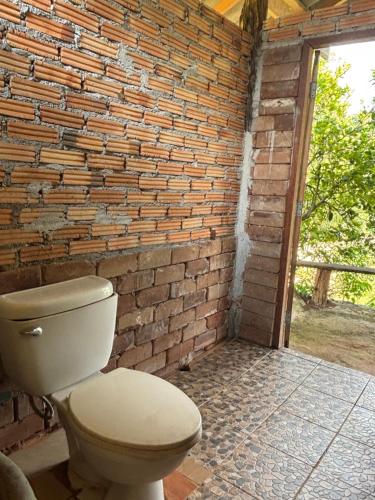 La salle de bains est pourvue de toilettes en face d'un mur de briques. dans l'établissement Maewin Farmer Homestay, à Ban Huai Rin