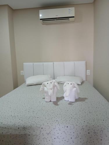 two stuffed elephants sitting on top of a bed at Liszen flats in Porto De Galinhas