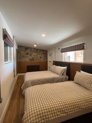 a bedroom with three beds in a room with a brick wall at Kells Yard in Feevaghmore
