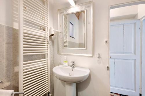 a white bathroom with a sink and a mirror at Bilocale Merlino in Finale Ligure