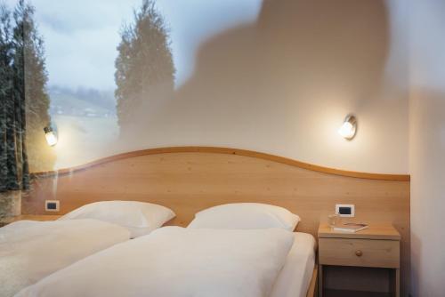 two beds with white pillows in a room with a window at Ciasa Willy App Sas La Crusc in La Villa