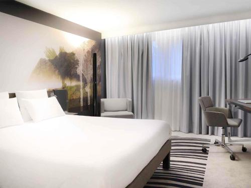 une chambre d'hôtel avec un lit et un bureau dans l'établissement Novotel Caen Côte de Nacre, à Caen