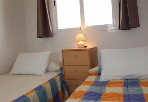 a bedroom with two beds and a lamp on a dresser at Fabulous sunny apartment in Almerimar