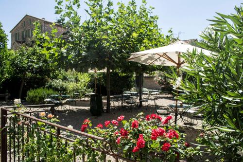 a garden with tables and chairs and an umbrella at Auberge De Tourrettes in Tourrettes-sur-Loup
